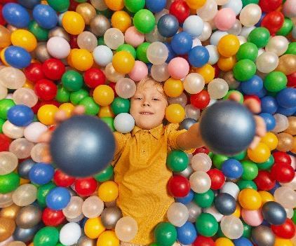 A kid dressed in yellow enjoying a ball pit - Kaldan Samudra Palace